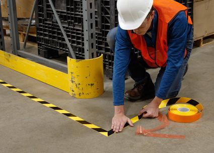 man applying striped floor tape