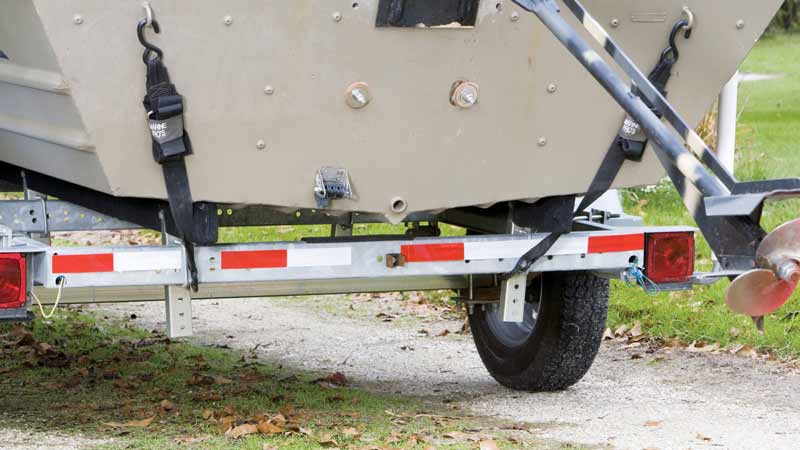 A close-up of the back of a boat trailer that has DOT-compliant red and white reflective tape.