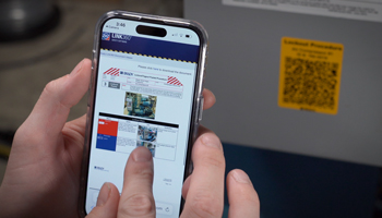 A phone scans a lockout tagout QR code to reveal the procedure on screen via Brady's Link 360 lockout tagout software.