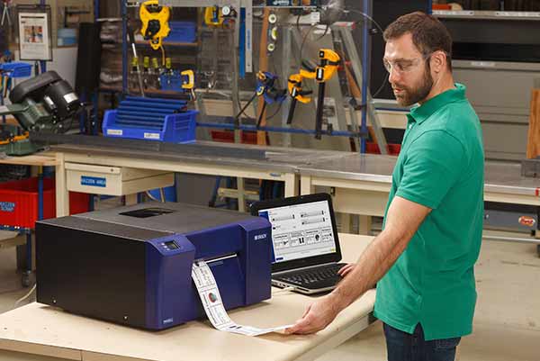 A man in a workshop printing labels on a Brady benchtop printer.