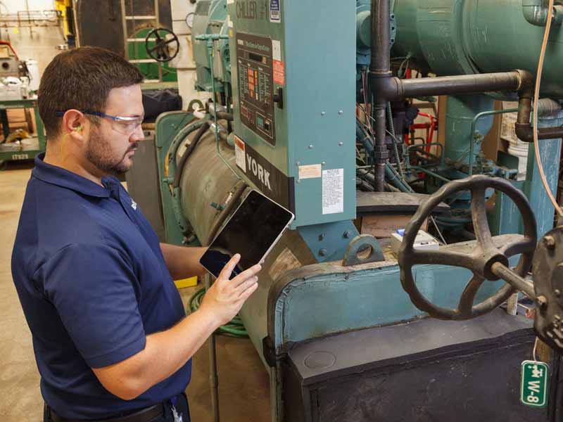 Industrial environment with an individual performing predictive maintenance on a machine.