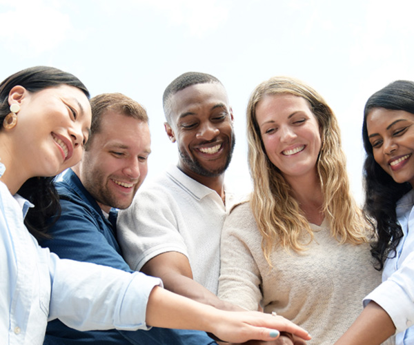 A group of diverse employees puts their hands together.
