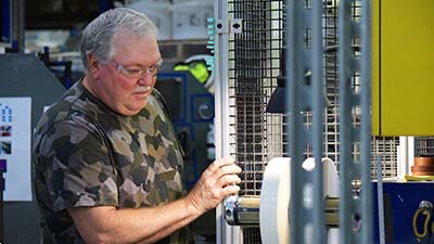 A man adjusts an industrial machine used for making labels.