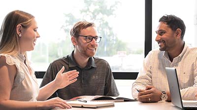 Three people happily sharing ideas in a meeting.