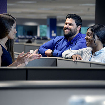 Three workers smiling as they converse.