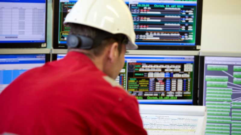 A worker overseeing a PLC control system.